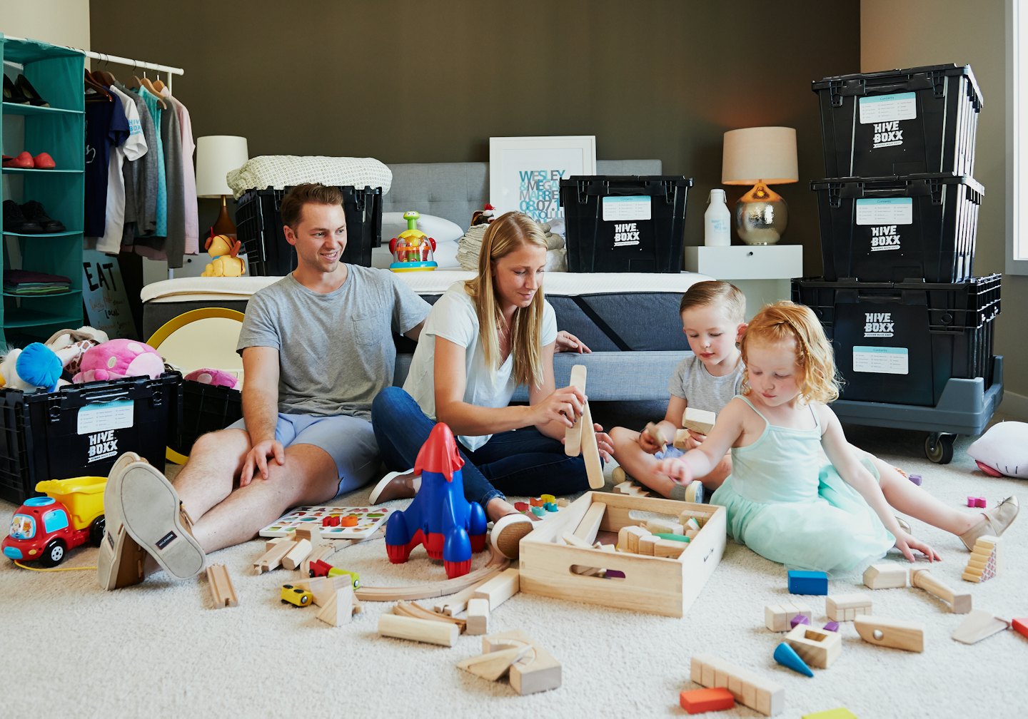 Famille assise sur un tapis déballant des cartons dans une nouvelle chambre.