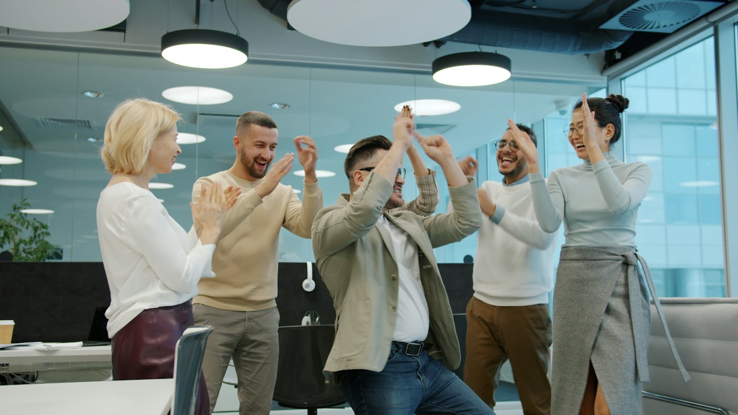 Une équipe d'affaires célèbre un succès en applaudissant dans un bureau lumineux.