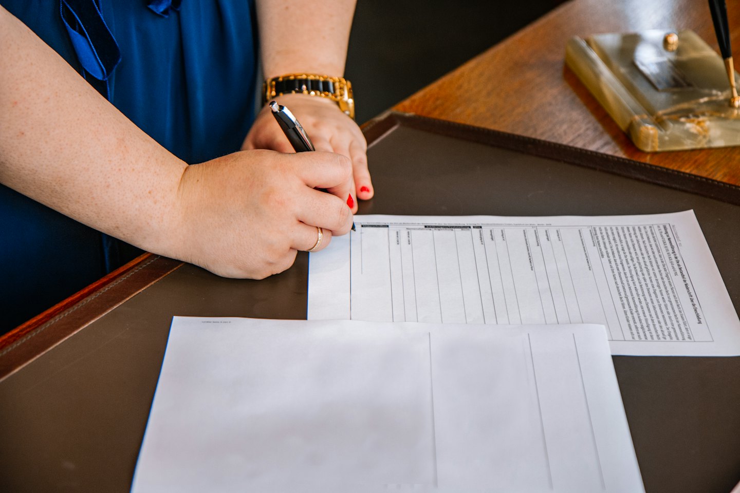 Mains signant un document sur un bureau en cuir.