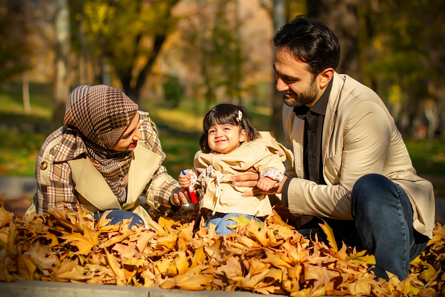 Des parents assis avec leur bébé souriant dans un parc.
