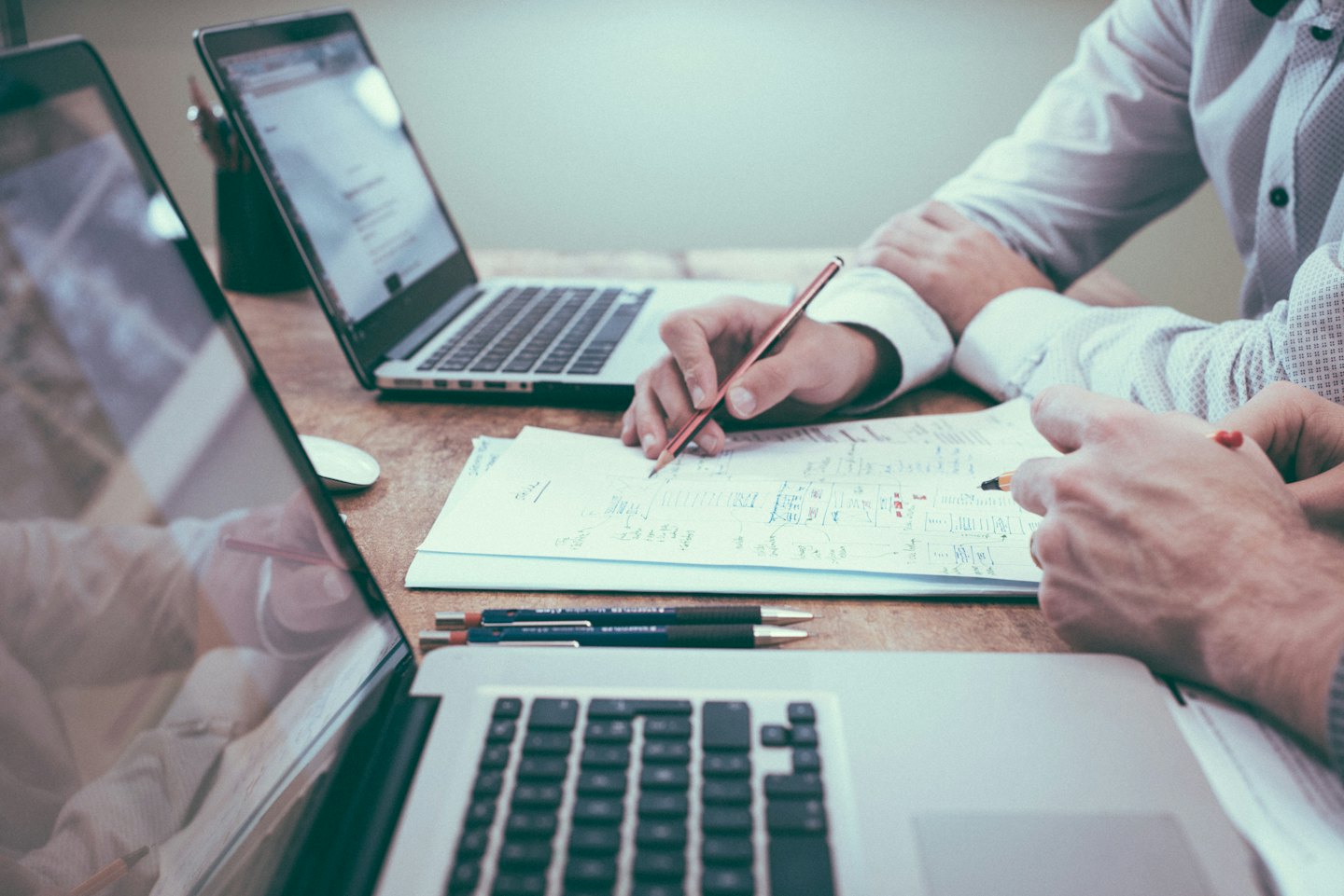 Deux professionnels collaborant sur des documents et des ordinateurs portables.