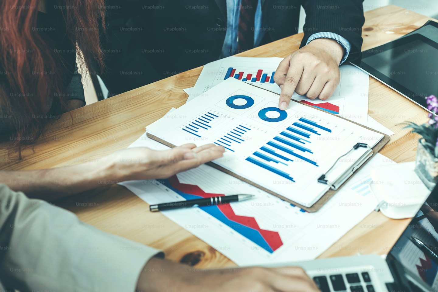 Deux professionnels discutent de données financières autour d'une table en bois.